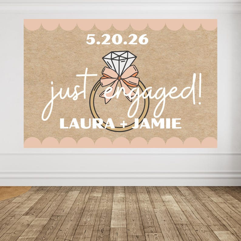 May include: A large sign with the words "just engaged!" in a cursive font, along with the names "LAURA + JAMIE" in a block font. The sign features a diamond ring graphic and the date "5.20.26". The background is a light brown color with a scalloped border.