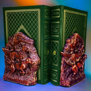 Könnte beinhalten: Ein Paar Bücherstützen aus Holz mit brauner Oberfläche. Die Bücherstützen zeigen ein Relief von Hunden, die durch einen Wald rennen. Die Bücherstützen halten zwei grüne, ledergebundene Bücher mit goldenen Lettern. Die Bücher sind betitelt mit "The Arthur Conan Doyle  The Complete Sherlock Holmes" und "Great Cases of Sherlock Holmes".