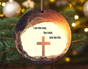 May include: A round, wooden Christmas ornament with a rustic, textured surface. The ornament features a white background with a brown cross and the text "I am the way, the truth, and the life. John 14:6".