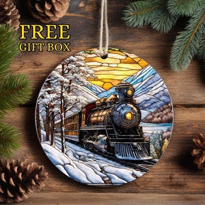 May include: A round Christmas bauble depicting a vintage steam train travelling through a snowy mountain landscape in a stained glass style. The train is black and gold with a red caboose. The background is a blue sky with a yellow sun.