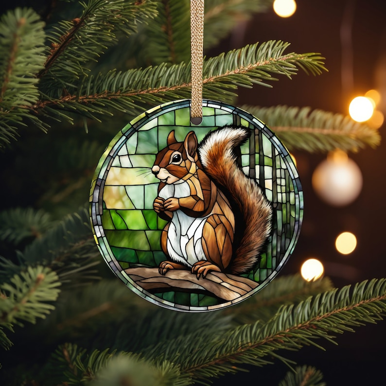 May include: A stained glass Christmas ornament featuring a squirrel with a bushy tail, sitting on a branch in a forest setting. The ornament is round and has a green, brown, and white color scheme.