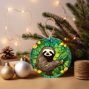 May include: A round Christmas ornament featuring a stained glass style illustration of a sloth in a green jungle setting with yellow flowers.