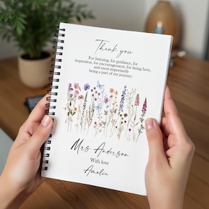 Può includere: Un quaderno a spirale bianco con una copertina floreale e la scritta "Thank you". Il testo esprime gratitudine ed è personalizzato con un nome e una frase finale. Il quaderno è aperto.
