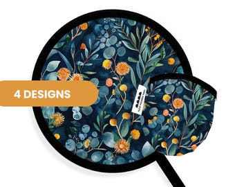 May include: A round folding fan with a dark blue background featuring a botanical pattern of green eucalyptus leaves and orange spherical flowers. The fan has a black border and a small pouch in the same print. A label reads 4 DESIGNS.