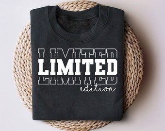 May include: A dark gray t-shirt with the text "I LIMITED LIMITED edition" printed in white.