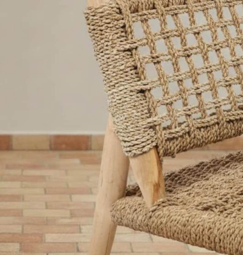 May include: Close-up of a woven chair with a natural, light brown color. The chair features a grid-like pattern on the backrest and seat, with wooden legs. The woven material appears to be made of natural fibers.