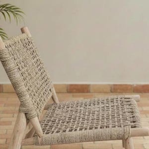 May include: A woven chair with a light brown, natural fiber seat and backrest. The chair has a wooden frame and a woven design. The chair is designed for relaxation and is suitable for indoor or outdoor use.