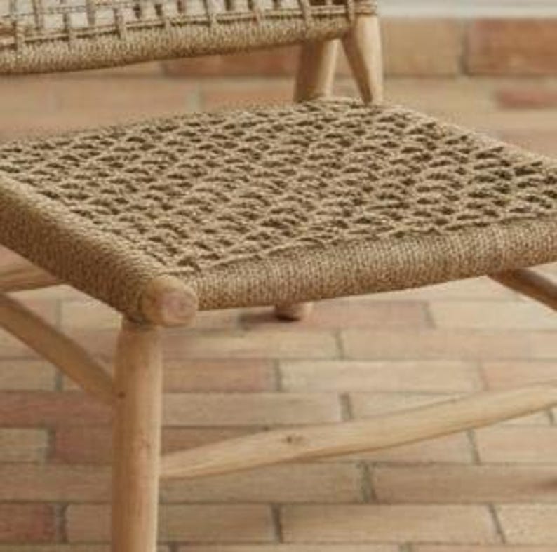 May include: Close-up of a wooden chair with a woven seat. The seat is made of a natural fiber, and the chair legs are light-colored wood. The chair is sturdy and has a simple design, suitable for various interior styles.