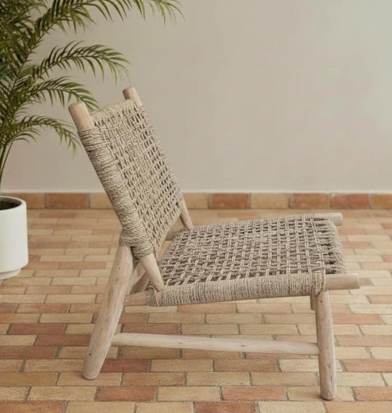 May include: A light-colored wooden chair with a woven seat and back. The chair has a simple design with four legs and a slatted back. The woven material is a neutral beige color, and the wood has a natural finish.