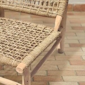 May include: Close-up of a woven chair with a natural fiber seat and back. The chair has a light-colored wooden frame and a woven pattern. The chair is designed for indoor or outdoor use.