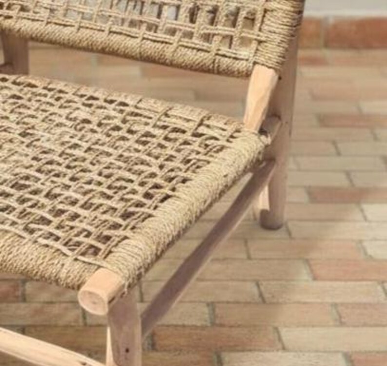 May include: Close-up of a woven chair with a natural fiber seat and back. The chair has a light-colored wooden frame and a woven pattern. The chair is designed for indoor or outdoor use.