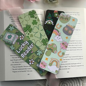 May include: Four green and white bookmarks with different designs. The bookmarks feature shamrocks, rainbows, mushrooms, a gnome, a pot of gold, and the text "Lucky Reader".