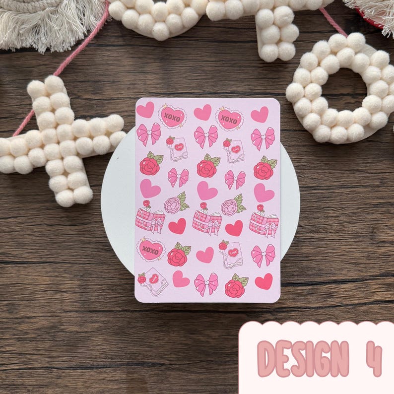 May include: A pink rectangular card decorated with pink hearts, bows, roses, and gift boxes. The card includes the text "XOXO" in heart shapes. The words "DESIGN 4" are at the bottom of the card.