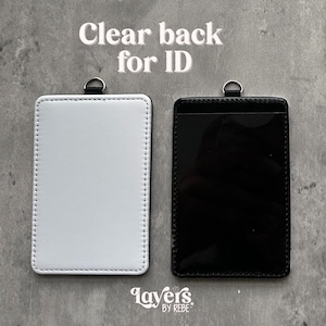 May include: Two ID badge holders, one white and one black, with a clear back for ID. The white holder has a stitched border and a silver ring at the top. The black holder has a clear front. The text "Clear back for ID" is at the top.