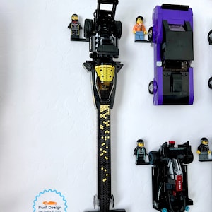 Shows the top fuel dragster car displayed with the minifig using the available wall mount. Other cars can also be seen in the photo but are not the intended focus.