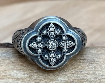 May include: A silver ring with a four-leaf clover design set with diamonds.