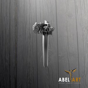 May include: A silver-toned ring with a detailed sculpture of a person on top. The ring's design features a long, cylindrical band. The background is a wooden surface. The logo "ABEL ART LUXURY JEWELRY DESIGN" is in the bottom right corner.