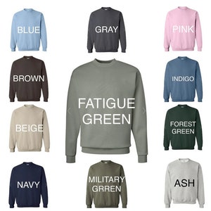 May include: A collage of 10 crewneck sweatshirts in various colors, including blue, gray, pink, brown, beige, navy, ash, forest green, fatigue green, and indigo. The sweatshirts are arranged in a grid pattern with the color name printed below each sweatshirt.