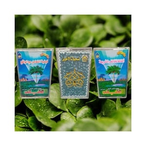 May include: Three clear plastic containers with Arabic text and palm tree imagery. The containers feature a blue and green colour scheme. The text includes the name "Al-Albani".