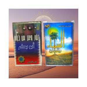 May include: Two cassette tapes with Arabic text and colourful designs. One tape has a blue and red cover with Arabic text. The other tape has a blue and yellow cover with a palm tree illustration and Arabic text. The background is a sunset.
