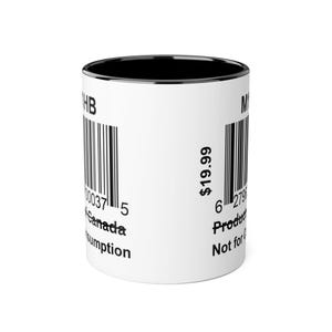 Peut inclure: Mug en céramique blanche avec intérieur et bord noirs. Le mug présente un code-barres et du texte, dont "Canada" et "Not for Consumption". Le mug est cylindrique et possède une anse.