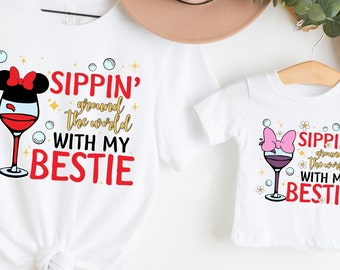 May include: Two white t-shirts with a graphic of a wine glass with a pink bow and the text "Sippin' around the world with my bestie".