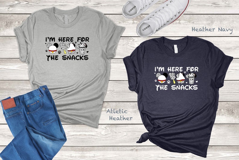 May include: Two t-shirts with the text "I'm here for the snacks" and a cartoon image of Mickey Mouse, a Dalmatian, a cupcake, and a milkshake. The t-shirts are in athletic heather and heather navy.