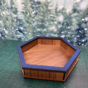 May include: A wooden, hexagonal tray with a dark blue trim. The tray is made of light brown wood and has a simple, modern design. The tray is likely used for decorative or organizational purposes.