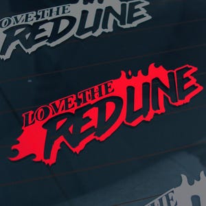 May include: A red and black decal featuring the words "LOVE THE REDLINE" in a bold, stylized font. The decal is designed for application to a vehicle's window or body. The image shows two decals, one in red and one in white.