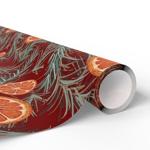 May include: Rolled wrapping paper featuring a repeating pattern of orange slices and evergreen branches on a deep red background. The design has a watercolor effect, with a metallic silver edge on the roll.