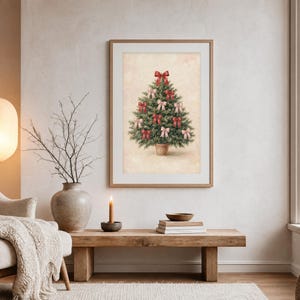 May include: A framed wall art print featuring a green Christmas tree in a pot, decorated with multiple red and light pink bows. The tree is centered on a textured, light beige background, enclosed within a simple light wood frame.