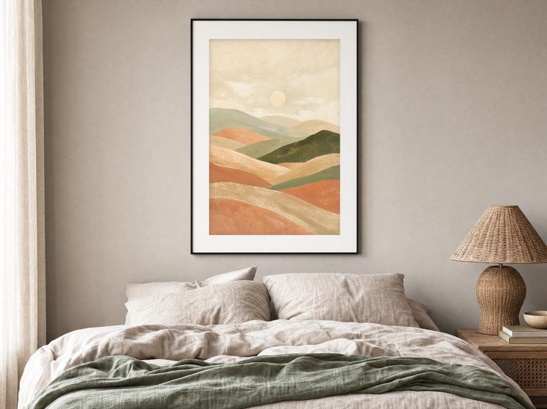 May include: A framed vertical wall art print featuring a watercolor landscape of rolling hills in shades of terracotta, sage green, and beige under a pale sun. The artwork is enclosed in a thin black frame and displayed on a neutral wall.