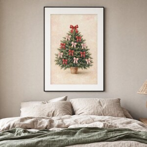 May include: A framed wall art print featuring a green Christmas tree in a terracotta pot, decorated with multiple red and light pink bows. The tree is centered against a textured, light beige background within a simple black frame.