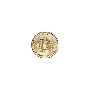 May include: A circular gold-colored metal coin featuring a prominent embossed Bitcoin symbol in the center. The surface of the coin displays intricate circuit board patterns radiating from the central B logo, with a textured, ridged outer edge.