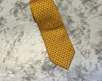 May include: A yellow tie with a repeating pattern of cocktail glasses in red, black, and yellow. The tie is made of a smooth fabric and is folded over itself.