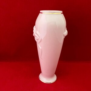 May include: A white porcelain vase with a gold rim and floral detailing. The vase has a slender, elegant shape.