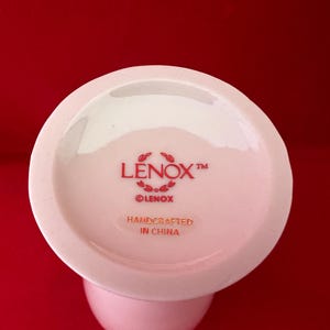 May include: White ceramic vase with a red Lenox logo and the text "Handcrafted in China".