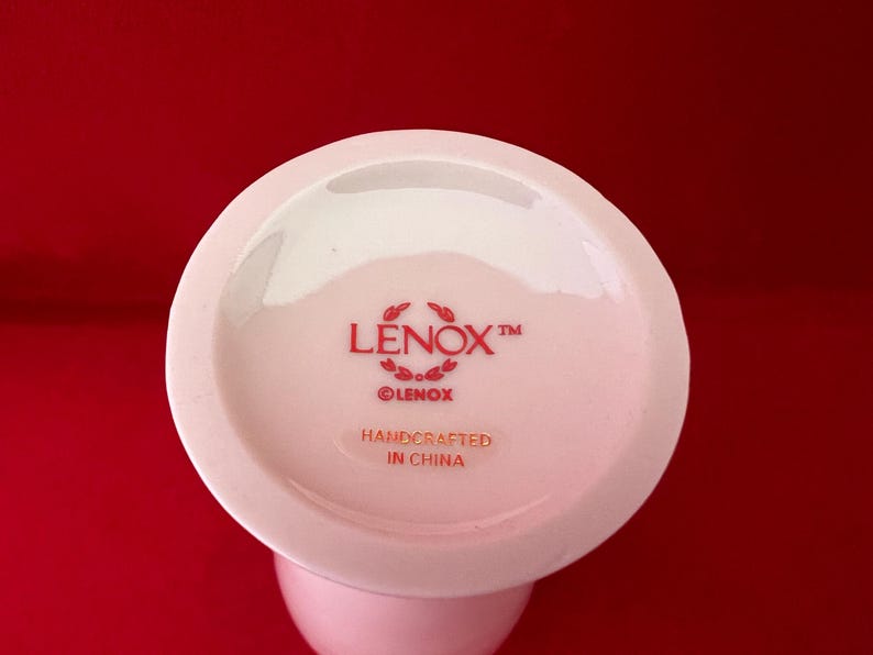 May include: White ceramic vase with a red Lenox logo and the text "Handcrafted in China".