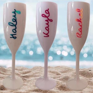Personalized acrylic champagne flutes with custom Love Island inspired names and colorful vinyl decals. Lightweight reusable 5 oz flutes perfect for bachelorette parties, bridal showers, girls trips, birthdays, and party favors. Customized drinkware with tropical summer aesthetic.