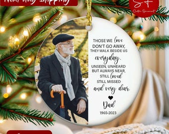May include: White ceramic ornament with a photo of an older man and a message that reads "Those we love don't go away, they walk beside us everyday. Unseen, unheard but always near, still loved, still missed and very dear. Dad 1965-2023"