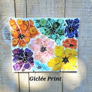 May include: A colorful giclée print of a flower design made from buttons. The print features a variety of colors, including orange, yellow, pink, purple, blue, and green. The buttons are arranged in a floral pattern, creating a unique and eye-catching design.