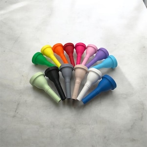 Puede incluir: Un conjunto de 14 boquillas de trompeta de plástico de colores. Las boquillas están dispuestas en círculo, con colores que van del verde al azul.