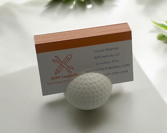May include: A white golf ball business card holder with a business card that reads "3DPCreativity 3D Printing With Creativity Connor Wiseman 3DPCreativity LLC Columbus, Ohio 3DPCREATIVITY@GMAIL.COM  IVITY.ETSY.COM"