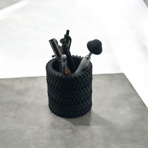May include: Black tire-shaped desk organizer with a variety of pens and a black and white stylus inside.