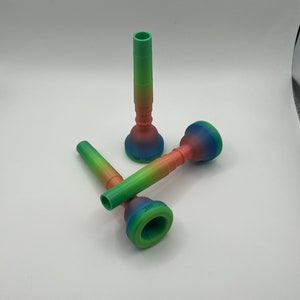 Könnte beinhalten: Drei farbige Trompetenmundstücke mit einem Farbverlauf von Grün, Blau und Rosa. Die Mundstücke sind aus einem weichen, flexiblen Material gefertigt und sollen den Klang und das Gefühl Ihrer Trompete verbessern.