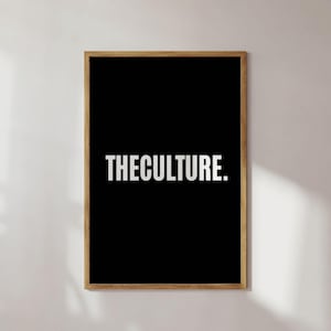 Könnte beinhalten: Ein gerahmter Kunstdruck mit schwarzem Hintergrund und dem weißen Text „THECULTURE.“. Der Rahmen ist hellbraun. Der Druck wird vor einer weißen Wand mit Schatten angezeigt.
