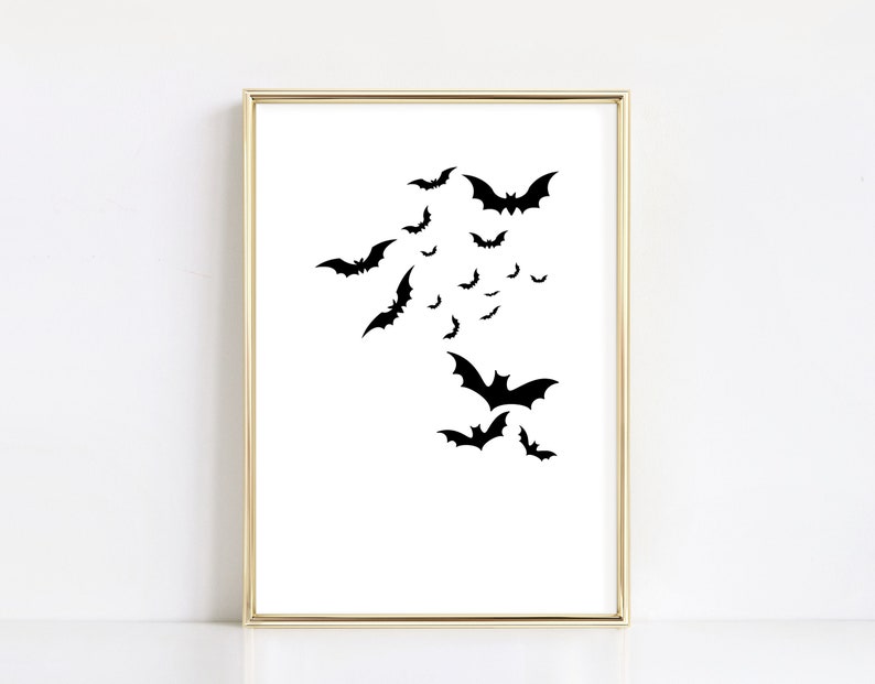 May include: A black and white printable wall art print featuring a silhouette of bats flying in a cluster. The print is framed in a gold frame.