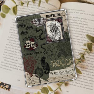 May include: A clear tablet case featuring a dark green collage of gothic illustrations including two skeletons in a frame, a black cat, a butterfly, skulls with red roses, a heart, moon phases, and text reading TEAM VILLIAN and My favorite color is morally gray.