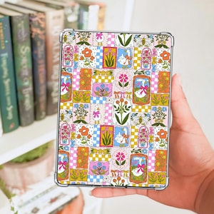 May include: A clear tablet case with a vibrant patchwork design. The design includes floral, bee, and goose motifs in a grid of pink, yellow, blue, and orange squares. The case is held in a person's hand, showcasing the colourful pattern.