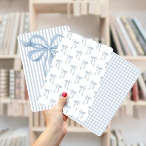 Könnte beinhalten: Drei Blätter mit blau-weißem Muster. Das erste Blatt hat ein blau-weiß gestreiftes Muster. Das zweite Blatt hat einen weißen Hintergrund mit einem sich wiederholenden Muster aus blauen Schleifen. Das dritte Blatt hat ein blau-weißes Karomuster.